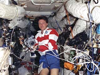 STS-86 mission specialist Michael Foale poses in the Mir space station Base Block with a camera.